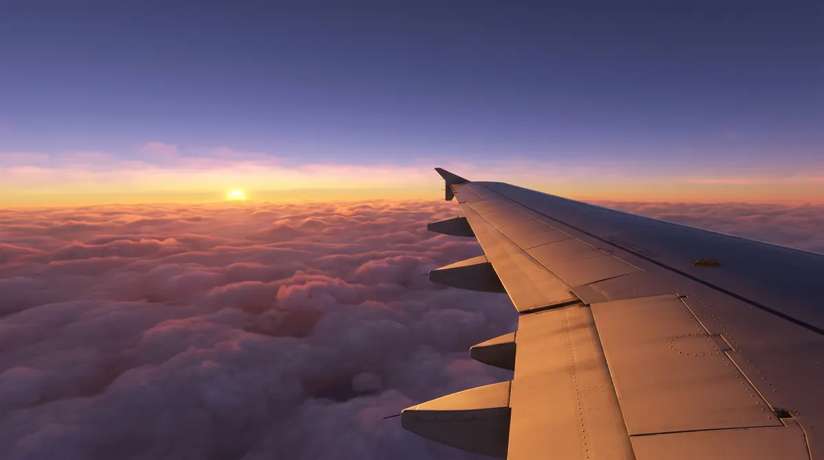 Aripa unui avion deasupra norilor, la apus